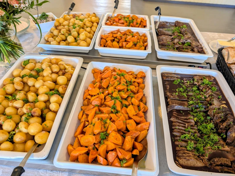 Pitopalvelun buffetpöytä perunoilla, porkkanoilla ja lihalla